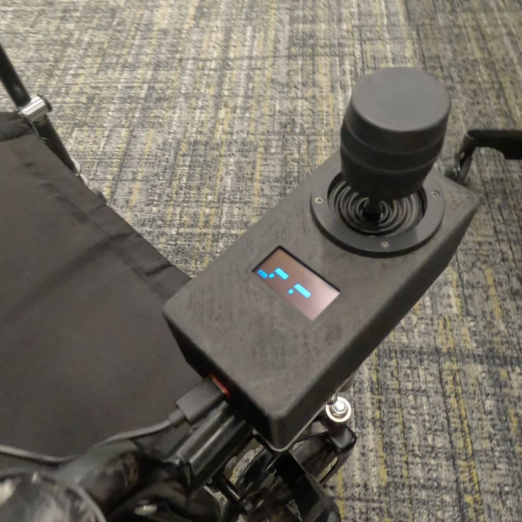 PAWE power attachment mounted on the front of a manual wheelchair